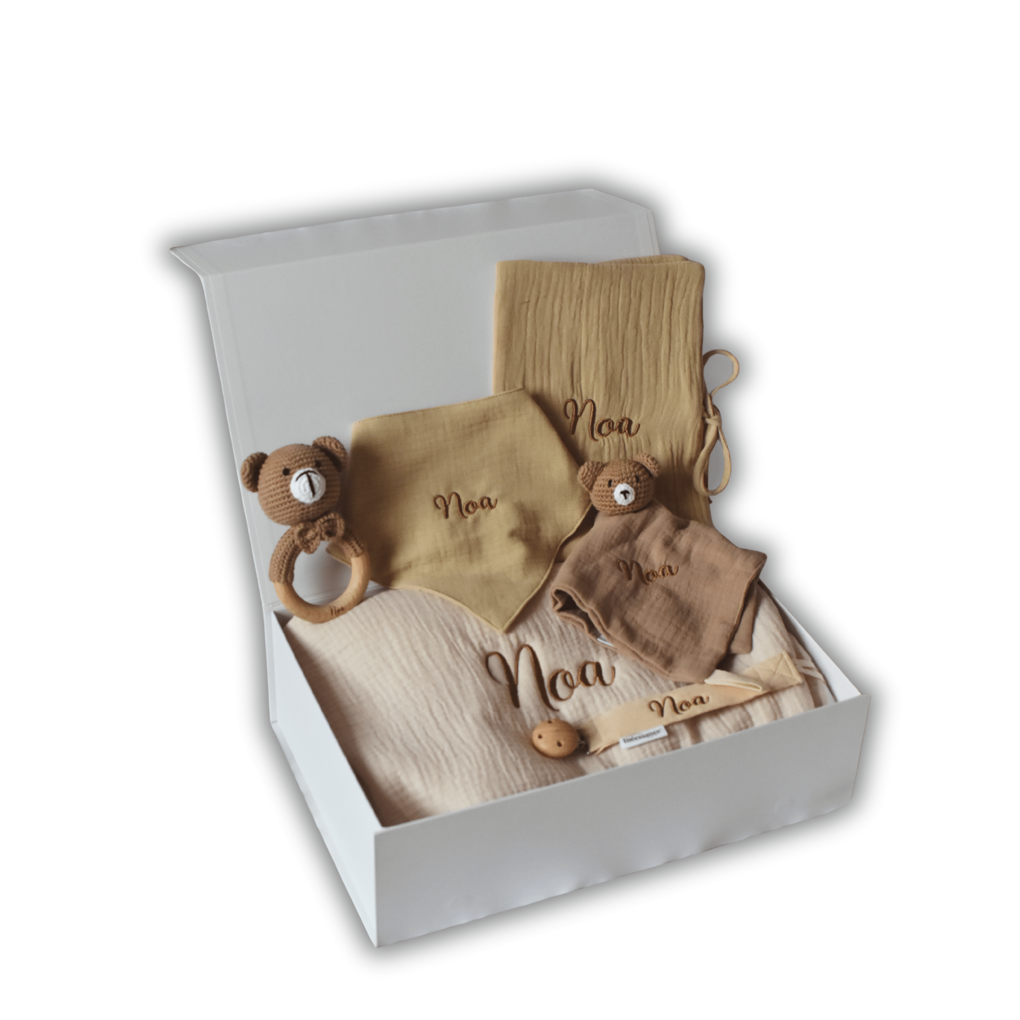 Coffret naissance personnalisé beige et caramel contenant gigoteuse, doudou, lange, bavoir, hochet ours en bois et attache-tétine brodés au prénom Noa, présentés dans une boîte cadeau blanche ouverte.