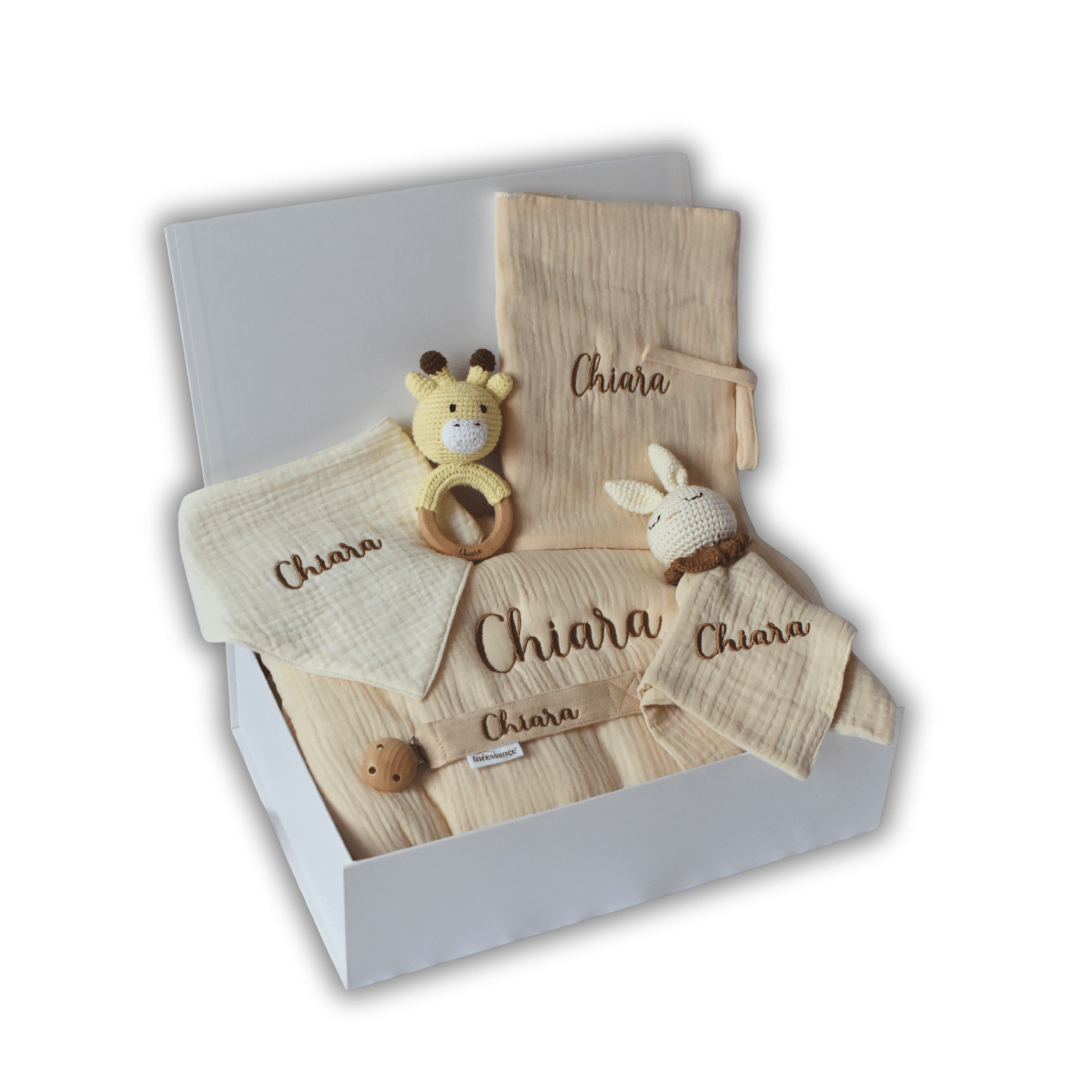 Coffret naissance personnalisé beige contenant gigoteuse, lange, bavoir, protège-carnet, hochet girafe, doudou lapin et attache-tétine brodés au prénom Chiara, présentés dans une boîte cadeau blanche ouverte.