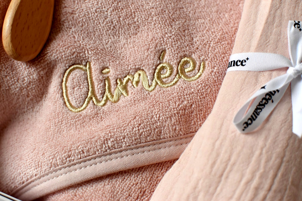 Broderie dorée du prénom Aimée sur cape de bain rose