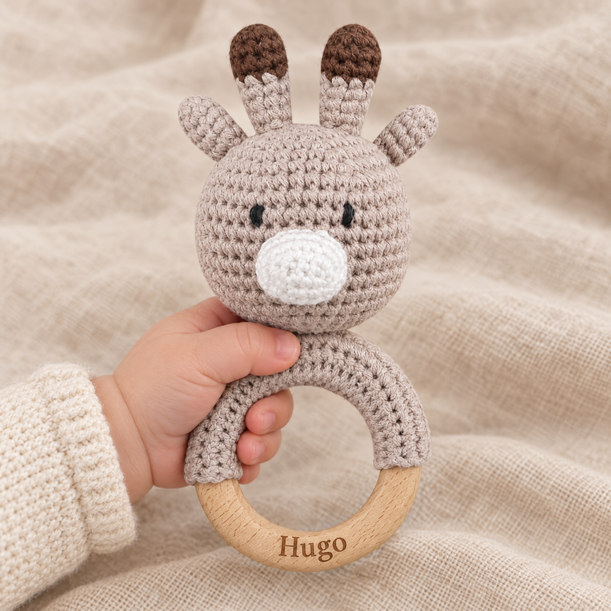Hochet en crochet personnalisé girafe taupe tenu par bébé, prénom gravé