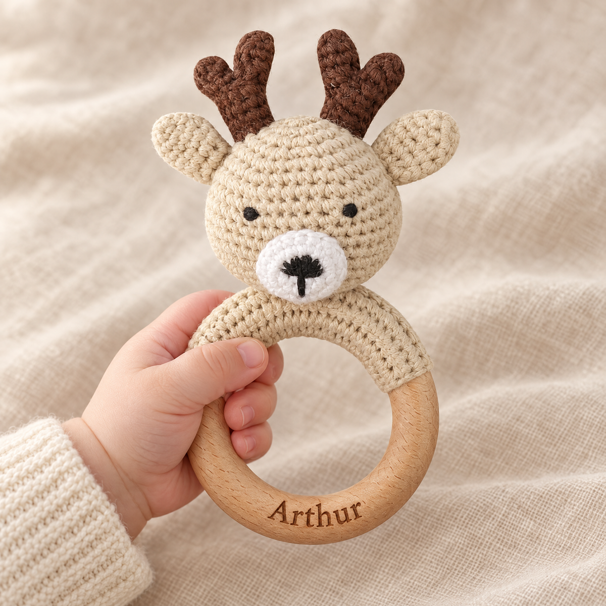 Hochet en crochet personnalisé cerf beige tenu par bébé, prénom gravé