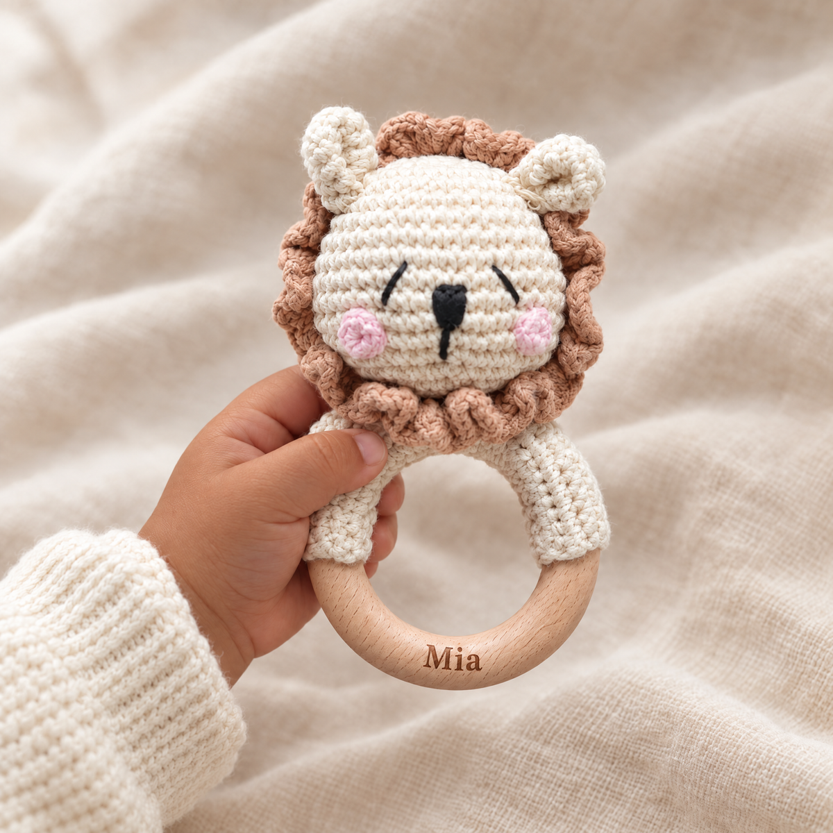 Hochet en crochet personnalisé lion timide joues roses tenu par bébé, prénom gravé