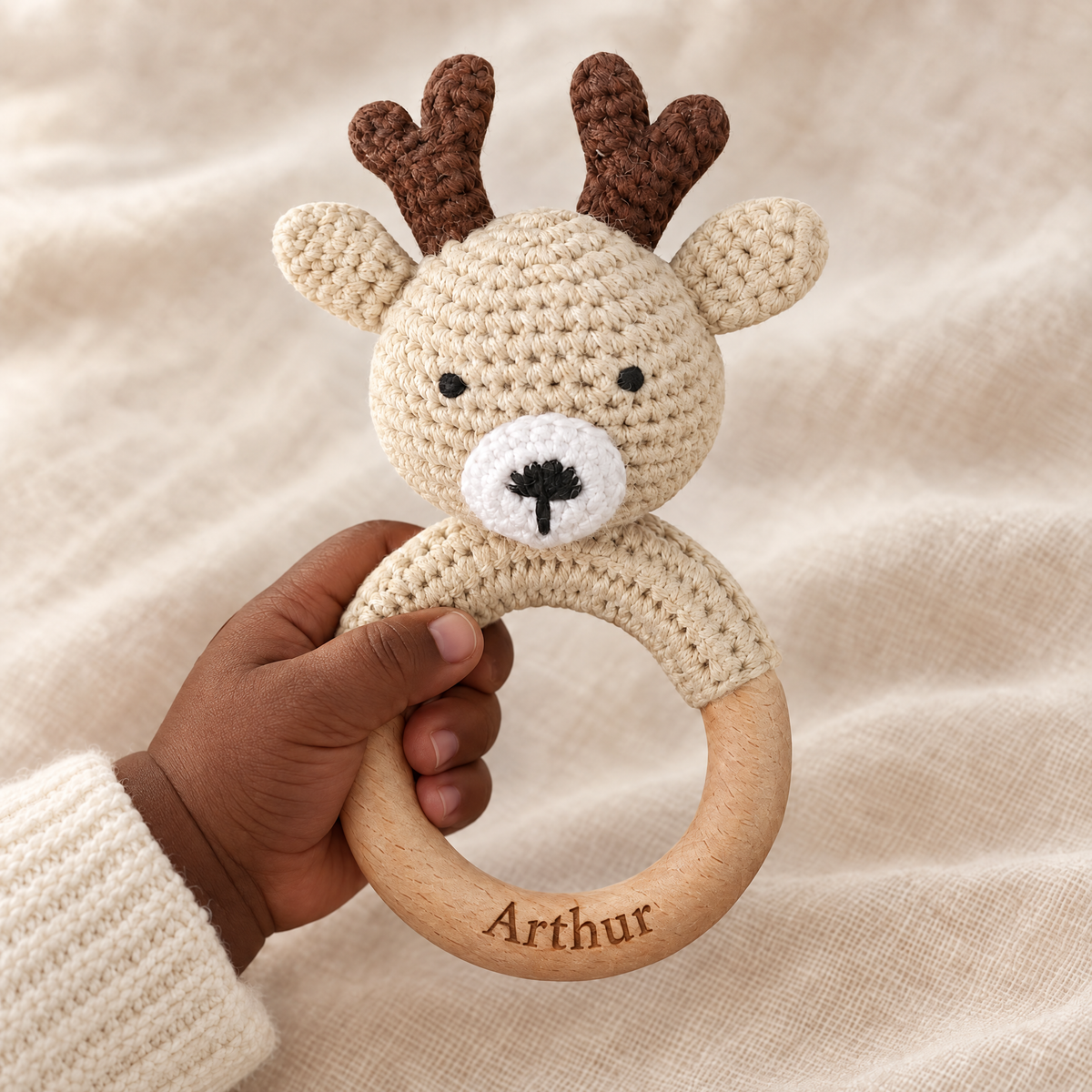 Hochet en crochet personnalisé cerf beige tenu par bébé, prénom gravé
